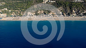 Aerial view of beautiful sandy beach with sunshades and soft turquoise ocean wave. Tropical sea in summer season on Kathisma beach