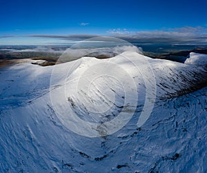 Aerial view of beautiful snow covered mountain peaks rising above a deep valley