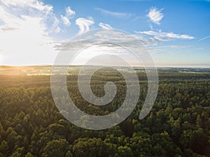 Aerial view of a beautiful sunset over rural landscape with forests and green fields