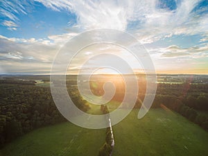 Aerial view of a beautiful sunset over rural landscape with forests and green fields