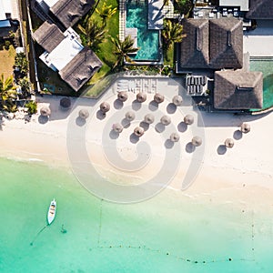 Aerial view of amazing tropical white sandy beach with palm leaves umbrellas and turquoise sea, Mauritius.