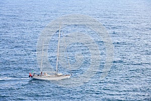 Aerial view of beautiful white sailboat in blue sea at bright sunny summer day.