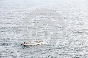 Aerial view of beautiful white sailboat in blue sea at bright sunny summer day.