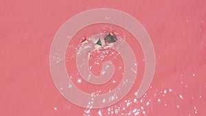 Aerial view. A beautiful young girl lies on in the pink lake, a bikini, sunglasses, pink clear water, a top view