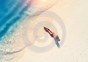 Aerial view of the beautiful young lying woman on the sandy beac