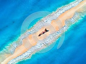 Aerial view of the beautiful young lying woman on the sandy beach