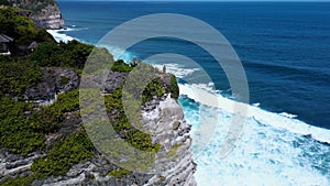 Aerial view of a beautiful young woman on a cliff looking out to the ocean.