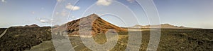 Aerial view of the Bermeja mountain of an intense red color, surrounded by lava fields, Lanzarote, Canary Islands, Spain