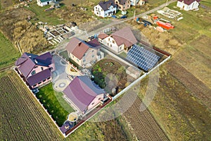 Aerial view of big blue solar panel installed on ground structure near private house