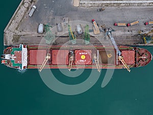 Aerial view of big cargo ship bulk carrier is loaded with grain of wheat in port