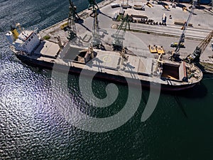 Aerial view of big cargo ship bulk carrier is loaded with grain of wheat in port at sunny day