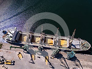 Aerial view of big cargo ship bulk carrier is loaded with grain of wheat in port at sunny day