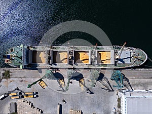 Aerial view of big cargo ship bulk carrier is loaded with grain of wheat in port at sunny day