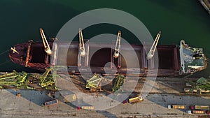 Aerial view of big cargo ship bulk carrier is loaded with grain of wheat in port at sunset