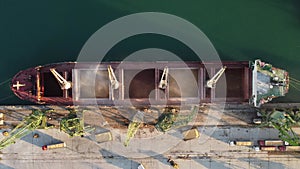 Aerial view of big cargo ship bulk carrier is loaded with grain of wheat in port at sunset