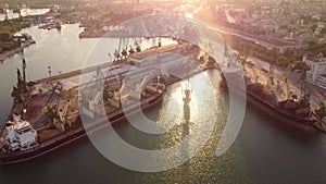 Aerial view of big cargo ship bulk carrier is loaded with grain of wheat in port at sunset