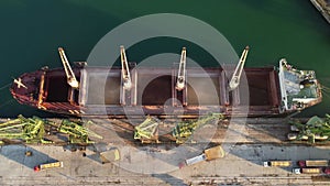 Aerial view of big cargo ship bulk carrier is loaded with grain of wheat in port at sunset