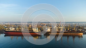 Aerial view of big cargo ship bulk carrier is loaded with grain of wheat in port at sunset