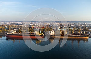 Aerial view of big cargo ship bulk carrier is loaded with grain of wheat in port at sunset