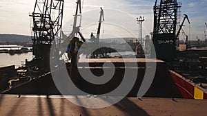 Aerial view of big cargo ship bulk carrier is loaded with grain of wheat in port at sunset