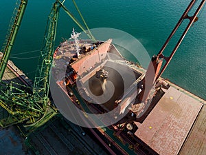 Aerial view of big cargo ship bulk carrier is loaded with grain of wheat in port at sunset