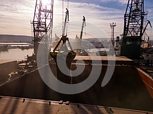 Aerial view of big cargo ship bulk carrier is loaded with grain of wheat in port at sunset