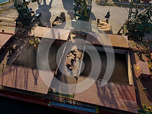 Aerial view of big cargo ship bulk carrier is loaded with grain of wheat in port at sunset