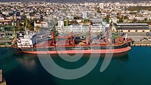 Aerial view of big cargo ship bulk carrier is loaded with grain of wheat in port at sunset