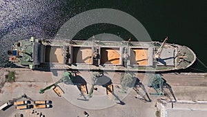 Aerial view of big cargo ship bulk carrier is loaded with grain of wheat in port at sunset