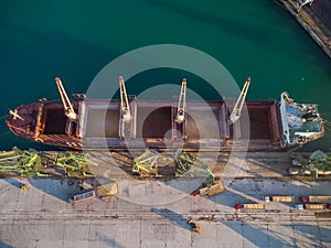 Aerial view of big cargo ship bulk carrier is loaded with grain of wheat in port at sunset
