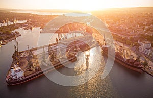 Aerial view of big cargo ship bulk carrier is loaded with grain of wheat in port at sunset