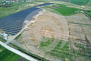 Aerial view of big electric power plant under construction with many rows of solar panels on metal frame for producing