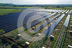 Aerial view of big electric power plant under construction with many rows of solar panels on metal frame for producing