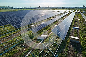 Aerial view of big electric power plant under construction with many rows of solar panels on metal frame for producing