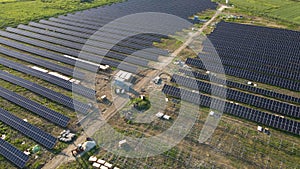 Aerial view of big electric power plant under construction with many rows of solar panels on metal frame for producing