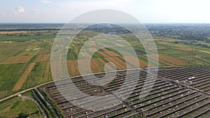 Aerial view of big electric power plant under construction with many rows of solar panels on metal frame for producing