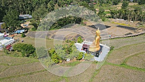 Aerial view of big gold Buddha statue and Pagoda at Wat Na Khu Ha Temple in Phrae , Thailand .