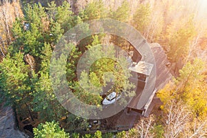 Aerial view of big modern luxuty cottage house between pine and birch trees in forest with boat on trailer parked at backyard