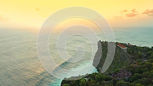 Aerial view on big ocean waves and rocks at sunset time in Uluwatu Temple, at the Bali island, Indonesia