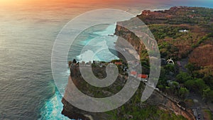 Aerial view on big ocean waves and rocks at sunset time in Uluwatu Temple, at the Bali island, Indonesia