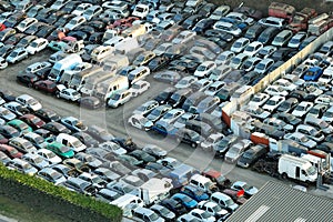 Aerial view of big parking lot of junkyard with rows of discarded broken cars. Recycling of old vehicles