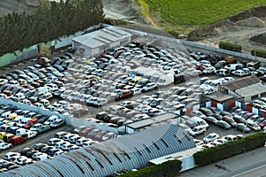 Aerial view of big parking lot of junkyard with rows of discarded broken cars. Recycling of old vehicles