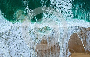 Aerial view of a big sandy beach with waves and a big ocean pool. Portuguese coastline