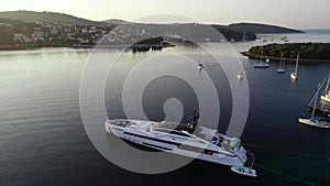 Aerial view of big white luxury yacht embarked in bay or harbour. Beautiful green island during summer season. Sailing experience