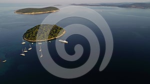 Aerial view of big white luxury yacht embarked in bay or harbour. Beautiful green island during summer season. Sailing experience