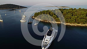 Aerial view of big white luxury yacht embarked in bay or harbour. Beautiful green island during summer season. Sailing experience