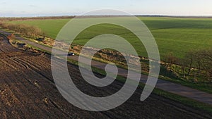 Aerial view of black car moving on the road countryside sunset green fields