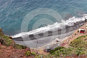 Aerial view of black stone beach Praia do Garajau, Madeira island, Portugal, Europe. Seen from Christ the King statue Cristo Rei