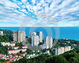 Aerial view of blue coast of Black Sea near  Sochi city with residential houses and recreation area under summer cloudy sky