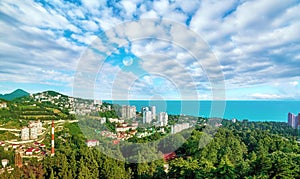 Aerial view of blue coast of Black Sea near  Sochi city with residential houses and recreation area under summer cloudy sky